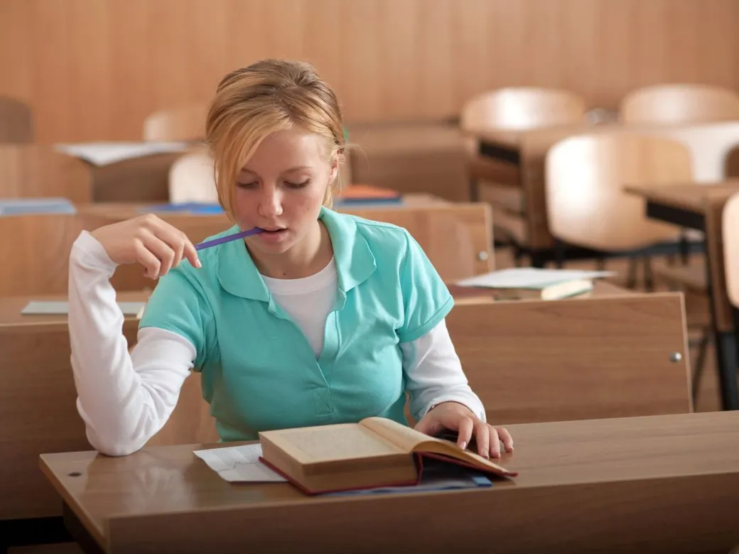 A pupil working through practice questions at a classroom desk.