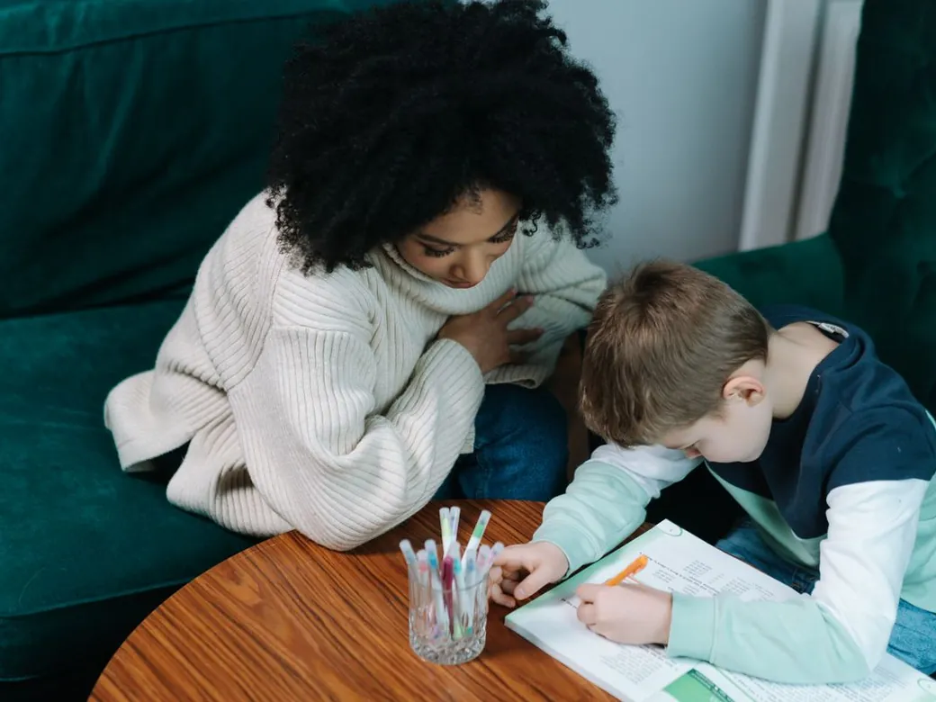 A tutor helping a child with written work at home.