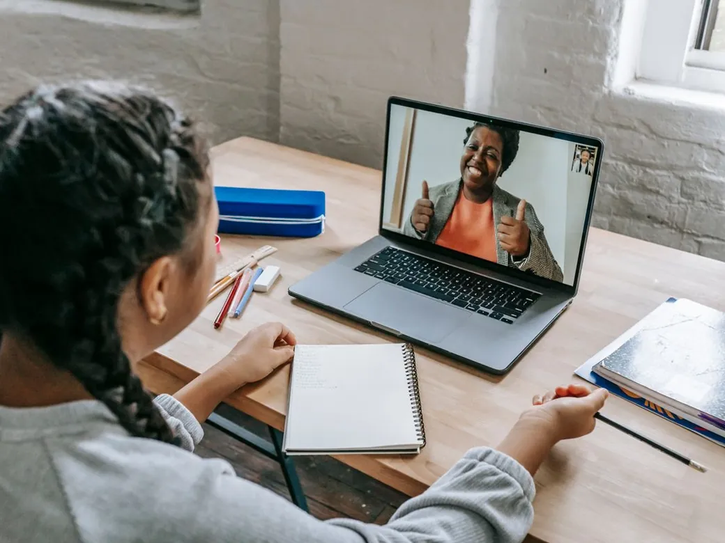 A pupil in an online lesson with a tutor on a laptop.